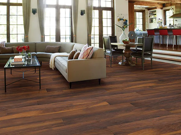 Stylish living room with polished hardwood flooring, modern furniture, and natural light coming from large windows.