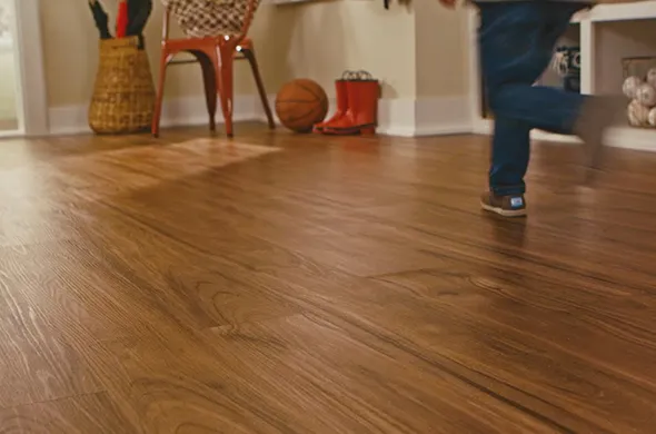 Polished hardwood floor with a child running across it in a cozy home setting, showcasing durable and expertly repaired flooring in Willowick, OH.