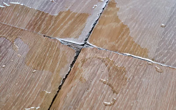 Close-up of reliable water-damaged floor repair in Willoughby OH, showing a worker repairing a damaged vinyl floor section.